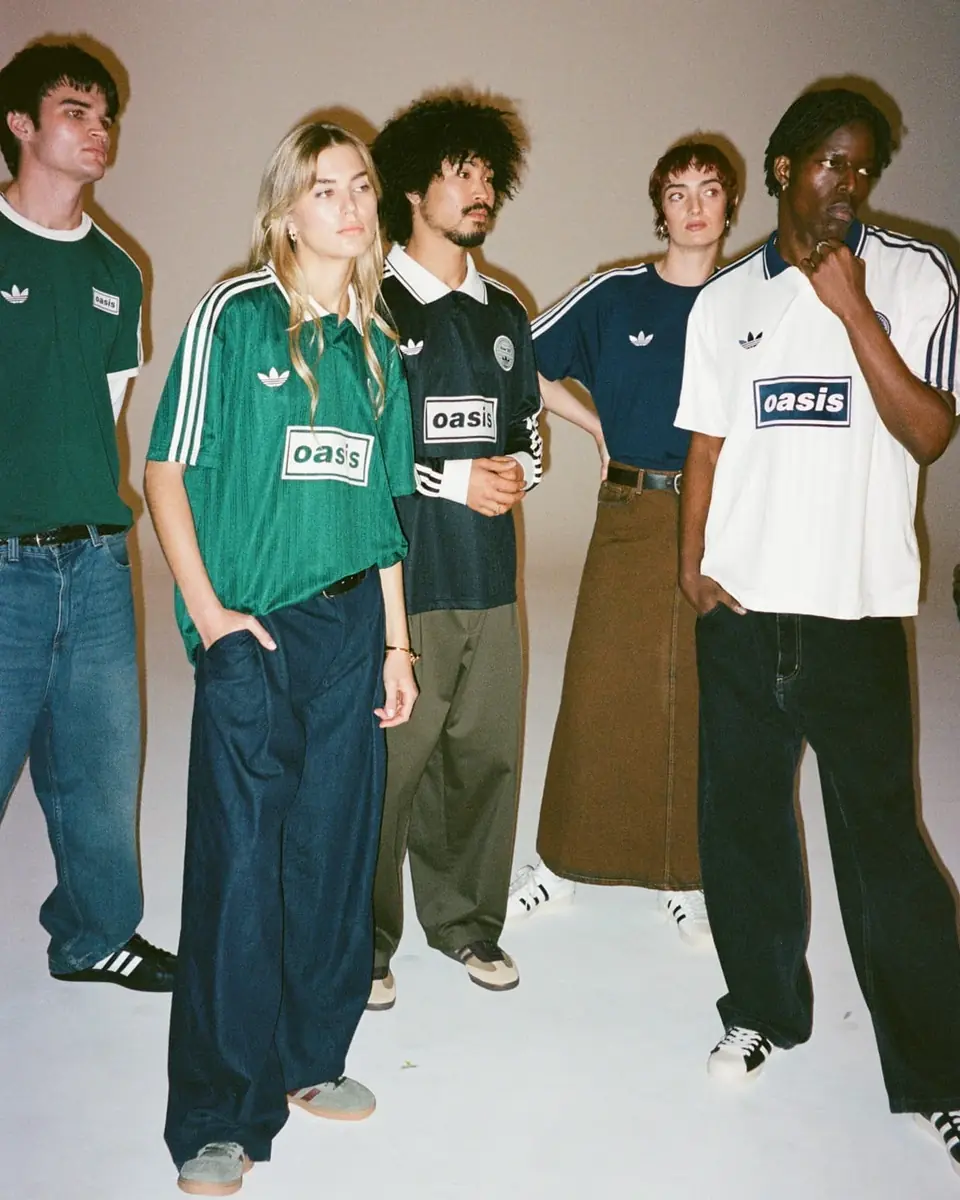 Cinco personas con las camisetas adidas × Oasis verde, azul marino, blanca y negra